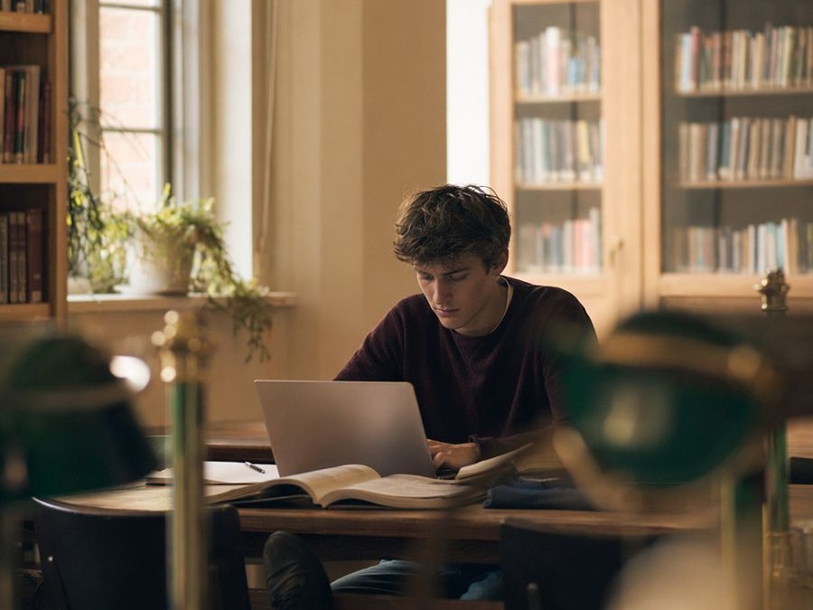 An upper-secondary student studies with focus at a table in the school library